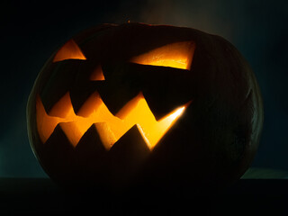 Glowing pumpkin jack-o-lantern on a dark background.