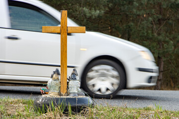 A roadside memorial cross with a candles commemorating the tragic death, on a background ride...