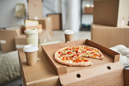 Close up background image of pizza on cardboard box as makeshift table in empty room while family moving in to new house