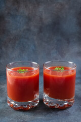 Two glasses with tomato juice on a blue grunge background. Copy space.