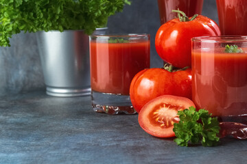Tomato juice in glasses, tomatoes and parsley on a grunge background. Close up.