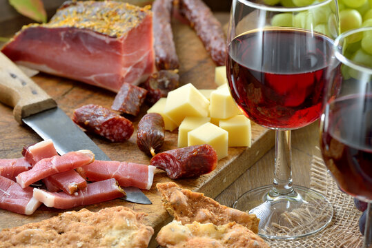 Brotzeit in S&uuml;dtirol mit typischen Spezialit&auml;ten wie Speck, Bergk&auml;se, Kaminwurzen und Sch&uuml;ttelbrot serviert mit Rotwein - South Tyrolean snack with bacon, mountain cheese and the crunchy rye bread 