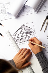 Woman architect draws a sketch of a house on paper. A designer is working on a construction project at his desk. Blueprints.