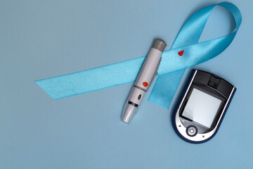 Close up top view of concept for World Diabetes Day 14 November. Blue tape with blood drops and a glucometer on a blue background.