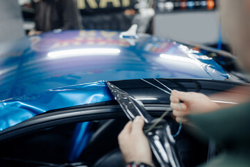 Obraz premium Car wrapping specialist putting vinyl foil or film on car. Selective focus.