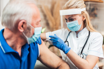 Female doctor vaccinating senior male patient. Coronavirus, Covid-19 concept.