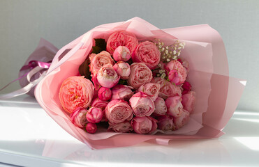 Bouquet of fresh roses wrapped in paper on white background