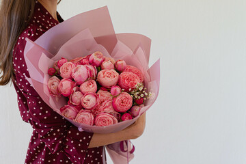 Very nice young woman holding big and beautiful bouquet of fresh roses, peony  in white and pink colors, cropped photo, bouquet close up