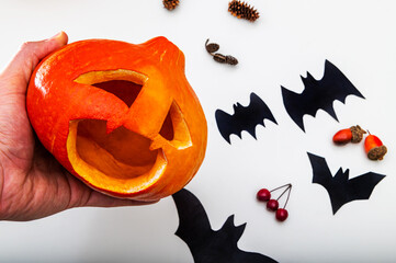 Close-up of a man's hand holding a ripe fresh pumpkin for Halloween