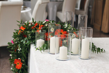 colorful fresh flower arrangement descending on wedding table and candles of different sizes