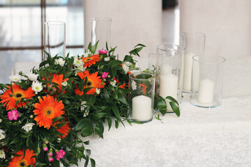 colorful fresh flower arrangement descending on wedding table and candles of different sizes