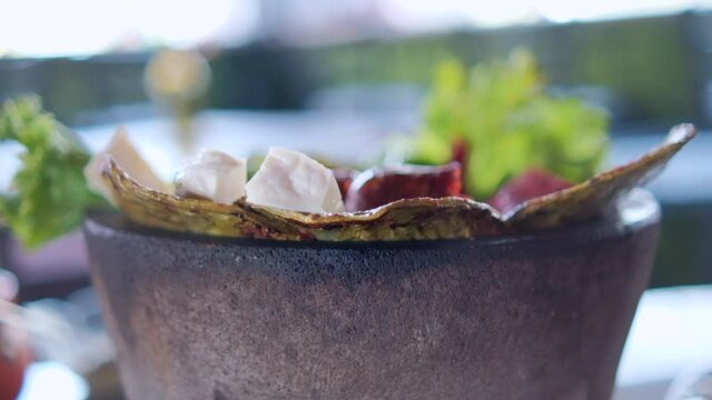 White cheese slices, lettuce, chorizo, and roasted nopales in Mexican molcajete