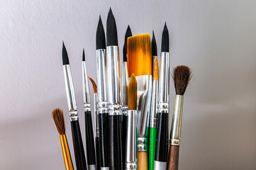 A set of different paint brushes isolated against a wall background. Layout