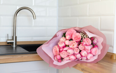 Valentine's Day and kitchen interior. For my Valentine. Close-up photo of a bouquet of  pink roses which lie on a kitchen table.