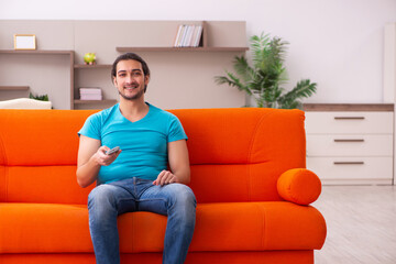 Young male student watching tv indoors