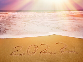 The numbers 2022 are written on the sandy beach against the background of the sea, ocean. Happy New Year and Vacation!