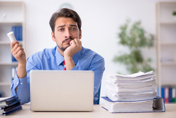 Young male employee unhappy with excessive work in the office