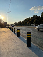Anti parking bollards on the sidewalk near automobile road under blue sky