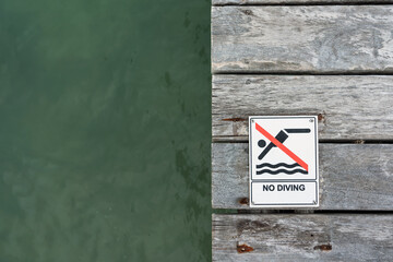 No Diving sign on a pier floor with ocean water in the background