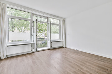 Interior shot of an empty room with white walls and a wooden floor with a balcony © Casa Media/Wirestock
