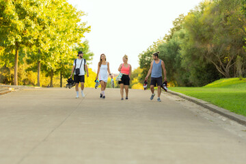 Four young people walking down a street with inline skates in their hand
