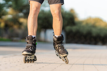 Fototapeta na wymiar Male legs on black inline skates on a pedestrian street