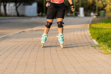 Fototapeta na wymiar Person skating with inline blue skates in a path next to a park