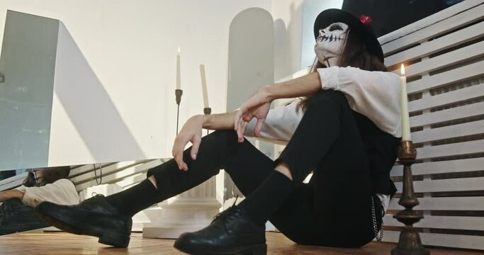 Dead spirit of a guy with unrequited love sitting on the ground in a professional studio with makeup