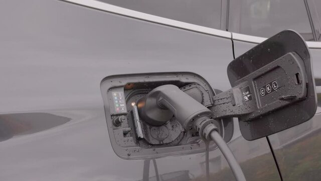 Close up view of man connecting charging cable to charging station for electric car. Sweden. 