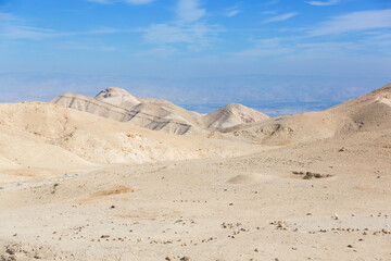 Fototapeta na wymiar Judean Desert in clear weather, Israel. White sand dunes and blue sky. Wadi Qelt land. Stony desert in the heat