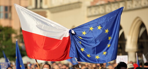 European union flag tied together with flag of Poland during street demonstration to support...