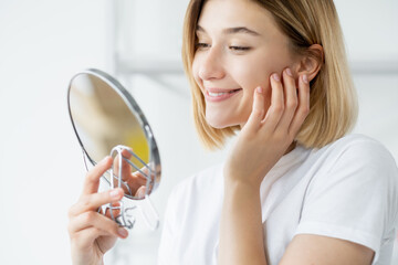 Morning skincare. Facial treatment. Skin rejuvenation. Satisfied smiling woman admiring radiant...