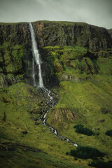 Obraz premium Waterfall in green mountains in Iceland. Beautiful nature landscape in the day