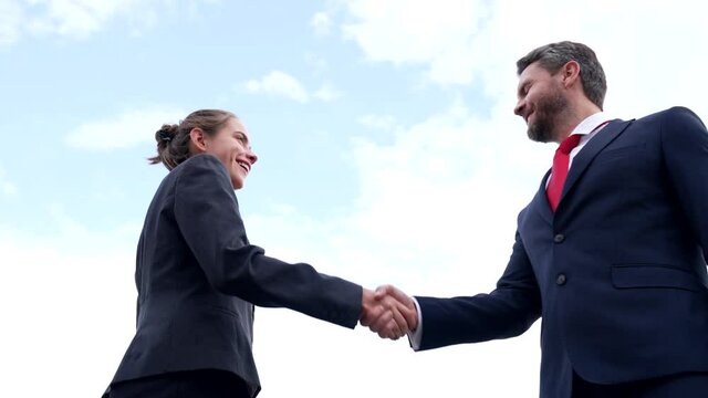 Happy professional girl and guy business partners shake hands on sky, handshaking