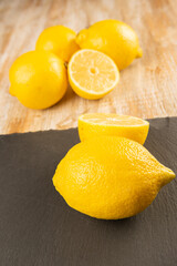 Whole lemon and lemon halved on slate plate and wooden background