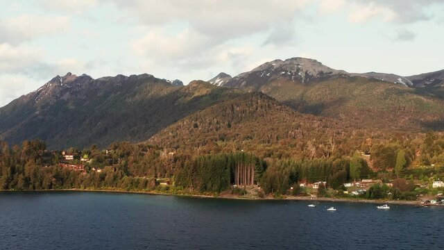 Aerial dolly drone shot of holiday homes and boats on the shore of Lake Nahuel Huapi near Villa La Angostura in Patagonia, Argentina at sunset