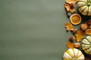 Autumn composition. Flat lay pumpkins, fallen oak leaves, nuts, dry oranges on vintage green background. Thanksgiving day greeting card template.