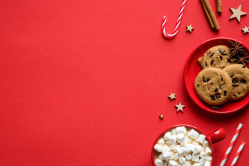 Christmas or New Year holiday banner design. Flat lay composition with oatmeal cookies, candy canes, hot cocoa with marshmallows on red background.