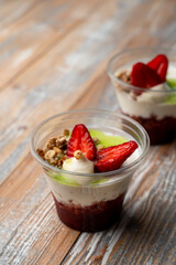 Healthy breakfast dessert in a glass, with cottage cheese, yoghurt and fresh berries, morning atmosphere, wooden background
