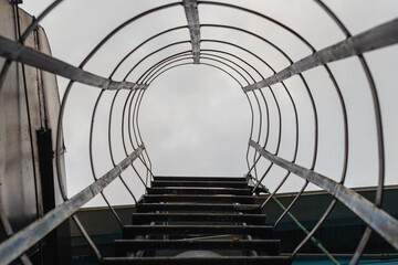 vista desde abajo de una escalera de emergencia, vista hasta el cielo nublado y gris