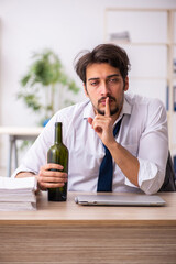 Young alcohol addicted employee sitting in the office