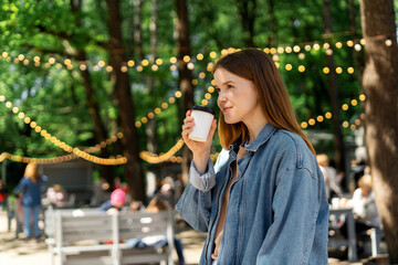    A woman in the park drinks coffee with herself