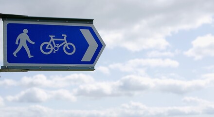 UK blue sign Pedestrian and cyclist route with an arrow pointing the way. Against a blue cloudy sky.