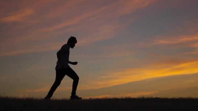 Silhouette shot of an Indian man running in front of the sun during the sunset. Man takes a jog before the sunrise. Athlete working out in the early morning and going for a morning jog. Health concept