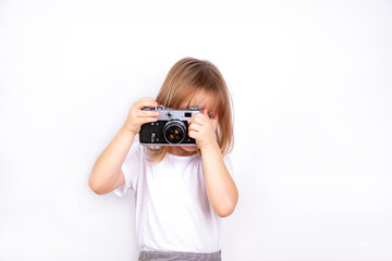A little girl holds a vintage camera in her hands and takes pictures.