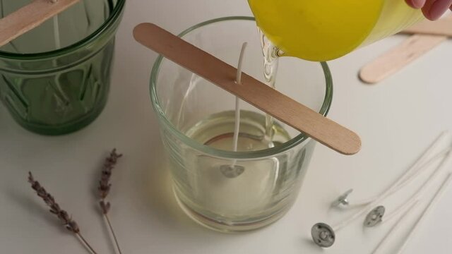 Pouring melted soy wax in glass. Crafting natural candle at home. Hobby.