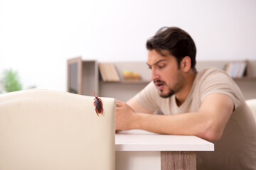 Young man and a lot of cockroaches at home