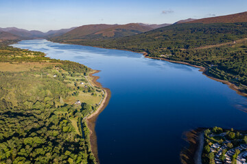 Aerial drone view of a beautiful, tranquil Scottish loch in the early morning sunshine (Loch Eil, Fort William)