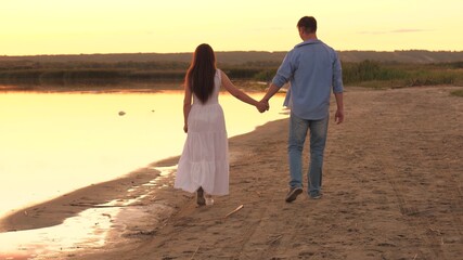 a man and a woman walk along the shore of the beach at sunset in the sky, romantic relationship of two people, happy family, cheerful people like to communicate, spend a carefree weekend together