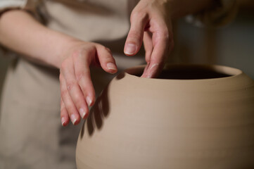 Fototapeta na wymiar Hands of a potter with a newly made pot